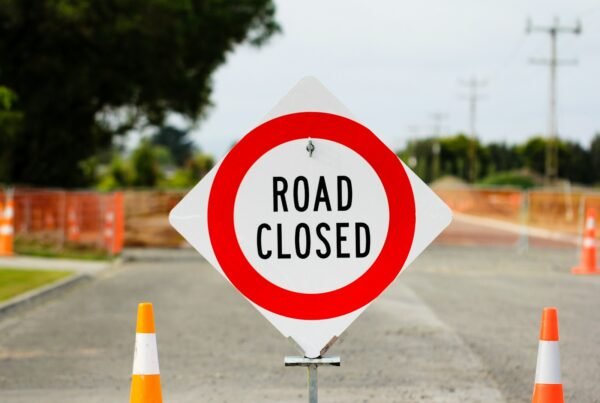 a road closed sign sitting on the side of a road