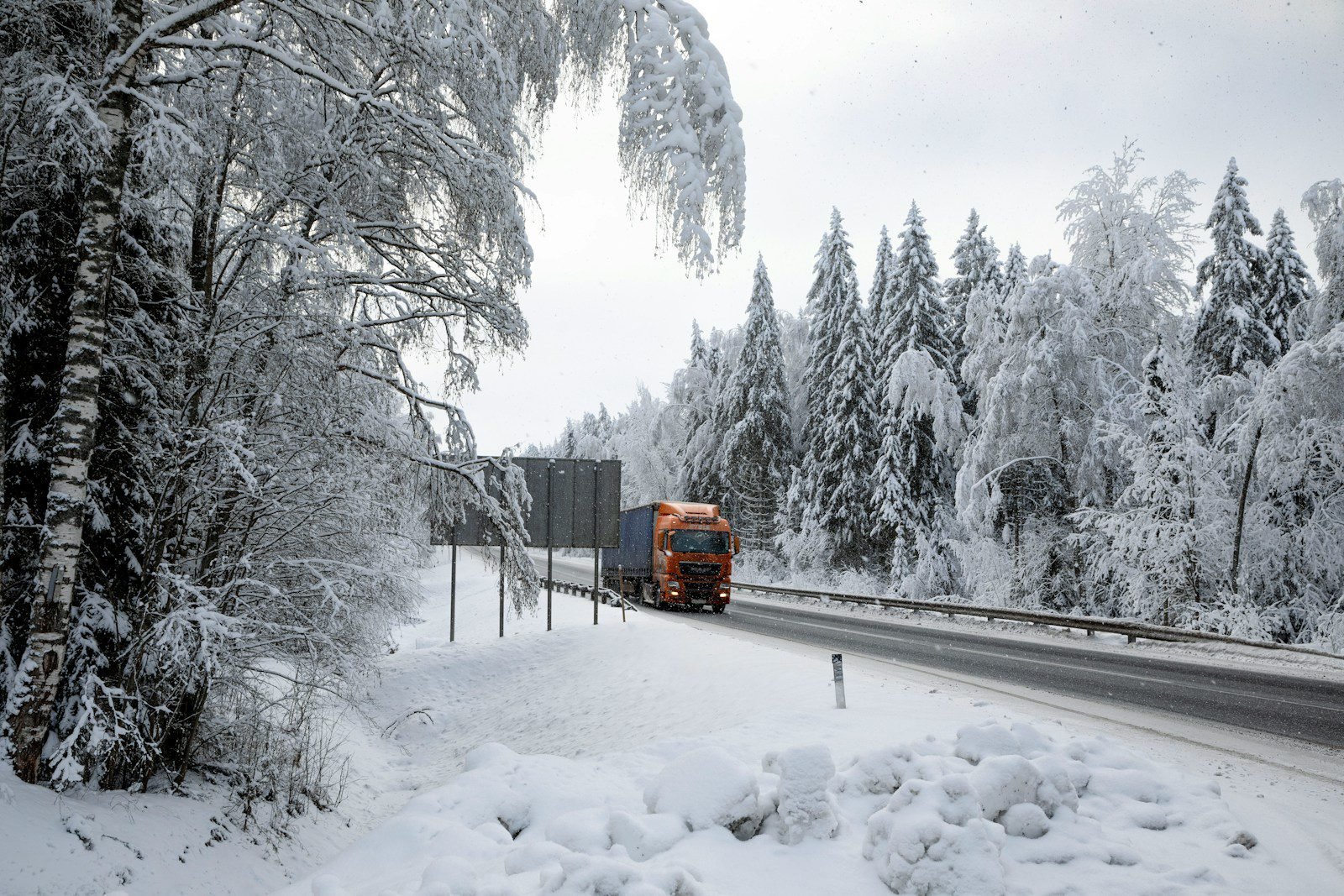 A truck driving down a road covered in snow