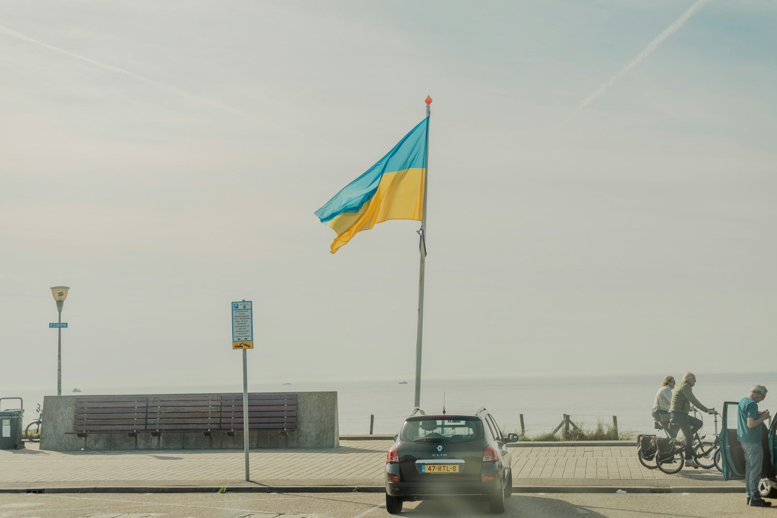 a car driving down a street next to a flag pole